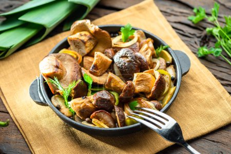 Photo for Cooked porcini mushrooms in the frying pan on the wooden table. Top view. - Royalty Free Image