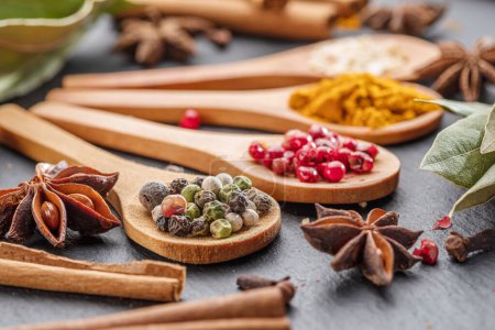 Photo for Various types of spices on wooden spoons on a gray stone table, great food background for your projects. - Royalty Free Image