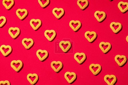 Foto de Pequeñas galletas en forma de corazón sobre un fondo rojo. Un hermoso fondo para el Día de San Valentín. - Imagen libre de derechos
