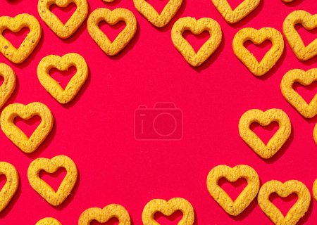 Téléchargez les photos : Petits biscuits en forme de coeur sur un fond rouge. Un beau fond pour la Saint-Valentin. - en image libre de droit