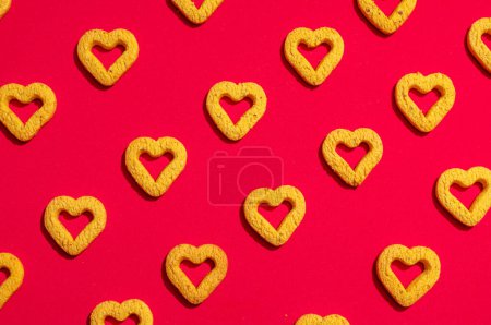 Téléchargez les photos : Petits biscuits en forme de coeur sur un fond rouge. Un beau fond pour la Saint-Valentin. - en image libre de droit