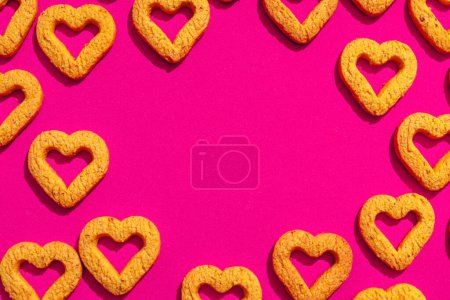 Foto de Pequeñas galletas amarillas en forma de corazón sobre un fondo rosa. Un hermoso fondo para el Día de San Valentín. - Imagen libre de derechos