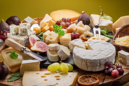 Foto de Variedad de quesos en rodajas con frutas, menta, nueces y cuchillos para cortar queso. Maravilloso fondo queso para sus proyectos. - Imagen libre de derechos