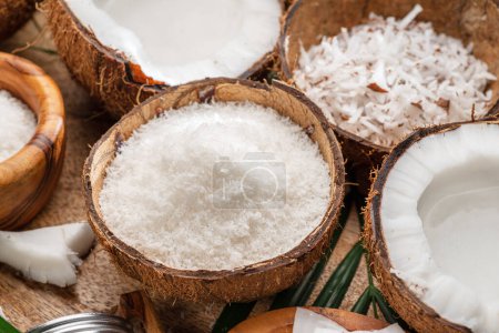 Photo for Fresh opened coconuts along with coconut slices, flakes and coconut leaves on a wooden table. Nice fruit background for your projects. - Royalty Free Image