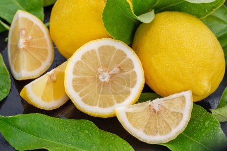 Téléchargez les photos : Fruits mûrs au citron avec des tranches et des feuilles de citron sur une table en pierre grise. Beau fond d'agrumes de fruits pour vos projets. - en image libre de droit