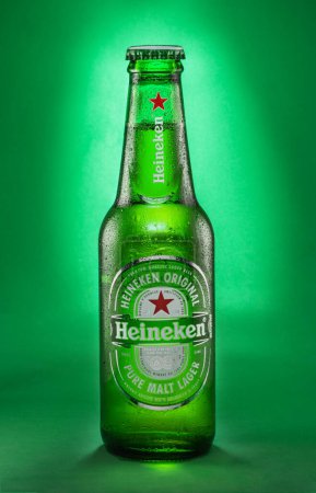 Téléchargez les photos : Portugal, Lisbonne, 9 décembre 2023 : Bouteille de bière blonde Heineken 0.33l avec gouttes isolées sur fond vert. Heineken est une marque de bière néerlandaise, l'une des plus populaires au monde. - en image libre de droit