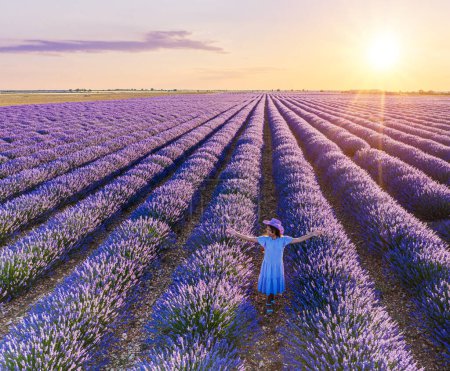 Photo for Young girl walking  in the lavender field and stunning sunset sky at the background. Brihuega, Spain. - Royalty Free Image