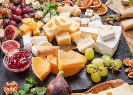 Téléchargez les photos : Variété de fromages tranchés aux fruits, menthe, noix et couteaux à fromage. Magnifique fond de fromage pour vos projets. - en image libre de droit