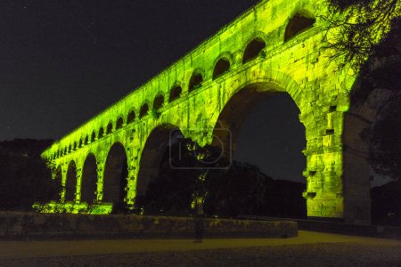 Photo for The Pont du Gard is an ancient Roman aqueduct, that is depicted  on five euro note. Bridge lit up at night time. Summer 2022. - Royalty Free Image