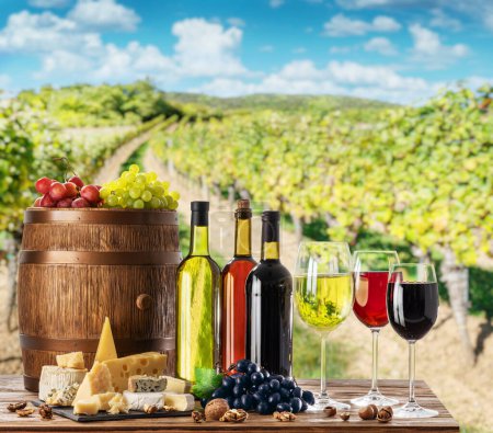 Photo for Wine still-life. Bottles of wine, glasses of wine and grapes on wooden table and blurred vineyard at the background. - Royalty Free Image