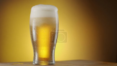 Téléchargez les photos : Verre de bière réfrigérée avec grosse tête de mousse isolée sur fond jaune. - en image libre de droit