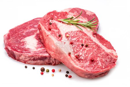 Photo for Raw ribeye steaks with pepper corns and rosemary isolated on white background. - Royalty Free Image