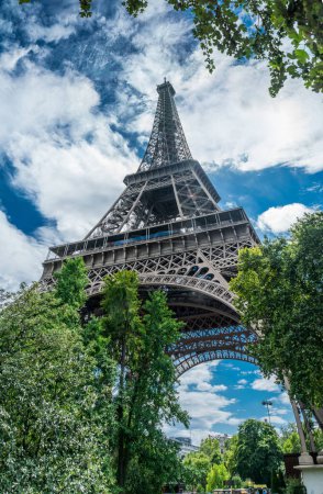 Foto de Torre Eiffel, el monumento más visitado de Francia. Vista inferior de cerca a través de verde verano exuberante. - Imagen libre de derechos