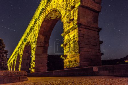 Le Pont du Gard est un ancien aqueduc romain, représenté sur un billet de cinq euros. Passerelle allumée la nuit. Été 2022.