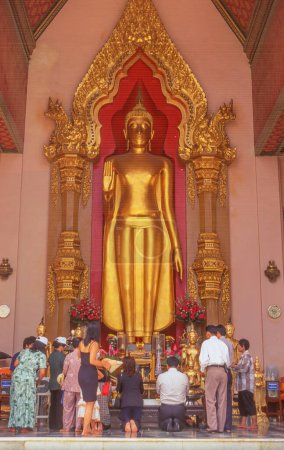 Foto de NAKHON PATHOM, TAILANDIA - 7 DE ABRIL DE 2023: Budistas orando frente a la imagen de Buda en pie en Phra Pathommachedi o Phra Pathom Chedi en la ciudad de Nakhon Pathom en la provincia de Nakhon Pathom, Tailandia. - Imagen libre de derechos
