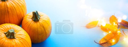 Foto de Banner de fiesta de acción de gracias o fondo de tarjeta de felicitación con calabaza de otoño y hojas de otoño sobre fondo azul - Imagen libre de derechos