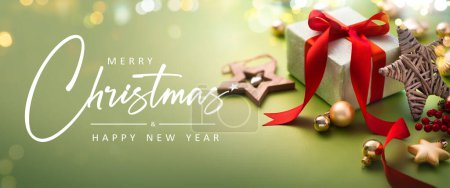 Foto de Tarjeta de felicitación de Navidad - Feliz Navidad y feliz año nuevo - Caja de regalo y adornos sobre fondo verde claro con luces mágicas - Banner, encabezado - Imagen libre de derechos