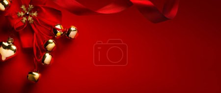 Foto de Tarjeta de felicitación de Navidad o diseño de banner de vacaciones; Decoración de árbol de Navidad de oro y cinta de seda sobre fondo rojo; Espacio de copia - Imagen libre de derechos