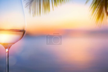 Foto de A glass of white wine at a tropical beach bar; Beautiful tropical sea sunset - Imagen libre de derechos