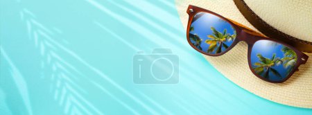 Foto de Concepto vacaciones y bandera de viaje de verano. Felices vacaciones en la playa tropical de arena. Sombrero de Panamá y gafas de sol con un reflejo de la playa tropical de arena y palmeras - Imagen libre de derechos