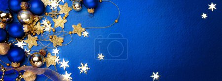 Foto de Banner de Navidad o diseño de tarjeta de felicitación. Rama de árbol de Navidad decorado bolas de color dorado y estrellas sobre fondo azul. Amplia maqueta de banner de Navidad, encabezado, volante - Imagen libre de derechos