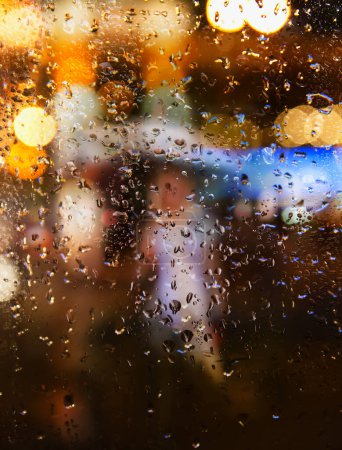 Foto de Fondo abstracto lluvia de otoño en la ciudad de la noche, silueta de una joven con un paraguas detrás de una ventana mojada - Imagen libre de derechos
