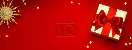 Foto de Banner de Navidad o tarjeta de felicitación de fondo con caja de regalo de Navidad y decoración dorada en fondo rojo - Imagen libre de derechos