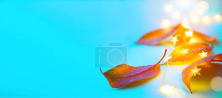 Foto de Arte feliz diseño de banner de acción de gracias. hojas amarillas otoñales y luces festivas sobre un fondo azul - Imagen libre de derechos