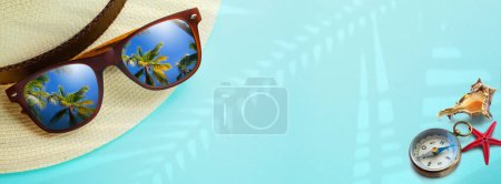Photo for Concept vacation and summer travel banner. Happy holidays on tropical sea beach. Panama hat, compass, sunglasses with a reflection of the sandy trovic beach and palm tree - Royalty Free Image
