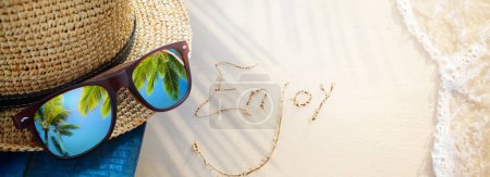 Foto de Enjoy tropical holiday, tropic holidays banner. sand beach from above with straw bucket hat and sunglasses, palm trees reflection, summer vacation concept banner with copy spac - Imagen libre de derechos
