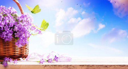 Foto de Fondo de la bandera de primavera. campanas azules flores de primavera en una cesta y mariposa mosca - Imagen libre de derechos
