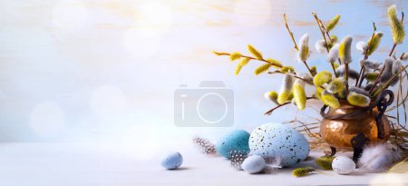 Foto de Feliz Pascua; Huevos de Pascua y flores de ramita sobre fondo de mesa azul - Imagen libre de derechos
