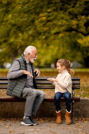 Photo for Handsome grandfather playing red hands slapping game with his granddaughter in park on autumn day - Royalty Free Image