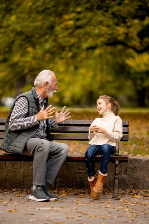 Photo for Handsome grandfather playing red hands slapping game with his granddaughter in park on autumn day - Royalty Free Image