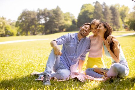 Foto de Feliz familia joven con linda hija divirtiéndose en el parque en un día soleado - Imagen libre de derechos