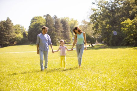 Foto de Feliz familia joven con linda hija divirtiéndose en el parque en un día soleado - Imagen libre de derechos