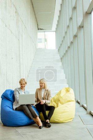 Photo for Two businesswomen working on laptop on lazy bags in the modern office - Royalty Free Image
