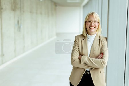 Téléchargez les photos : Jeune femme d'affaires debout dans le couloir du bureau - en image libre de droit