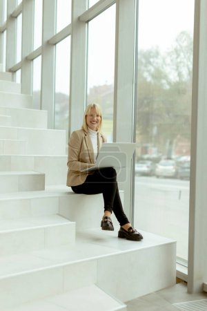 Téléchargez les photos : Femme d'affaires travaillant sur ordinateur portable sur les escaliers de bureau modernes - en image libre de droit