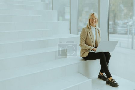 Photo for Businesswoman working on laptop on the modern office stairs - Royalty Free Image