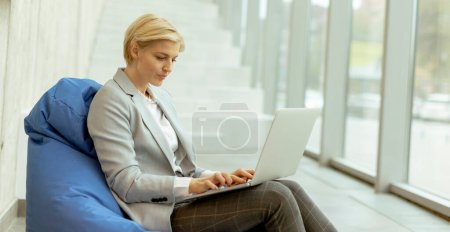 Photo for Businesswoman working on laptop on lazy bag in the modern office - Royalty Free Image