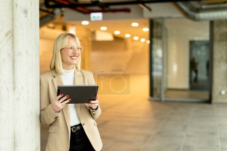 Téléchargez les photos : Femme d'affaires avec tablette numérique sur le couloir de bureau moderne - en image libre de droit