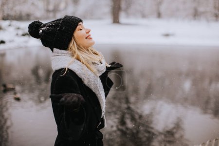 Foto de Pretty young woman in warm clothes enjoying in snow - Imagen libre de derechos