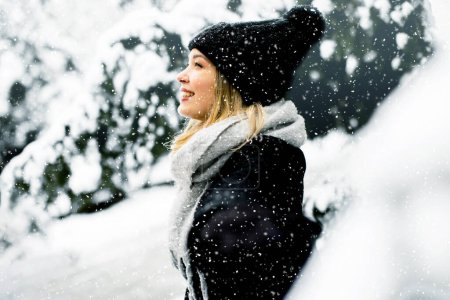 Foto de Pretty young woman in warm clothes enjoying in snow - Imagen libre de derechos