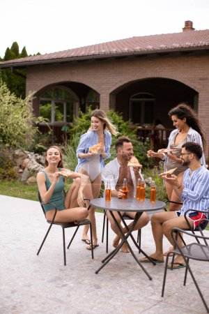 Photo for Group of happy young people cheering with cider and eating pizza by the pool in the garden - Royalty Free Image