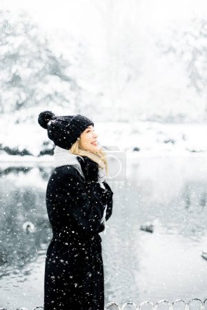 Photo for Pretty young woman in warm clothes enjoying in snow - Royalty Free Image