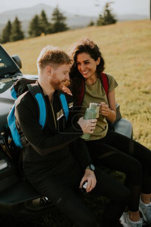 Téléchargez les photos : Handsome young couple relaxing on a terrain vehicle hood at countryside - en image libre de droit