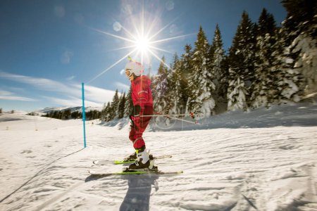 Une fille célibataire profite d'une journée ensoleillée d'hiver de ski, vêtue d'un équipement complet de neige avec des bottes de ski et des lunettes de soleil