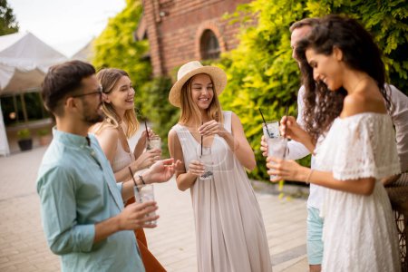 Téléchargez les photos : Groupe de jeunes se réunissent à l'extérieur pour profiter de la compagnie de l'autre et des verres rafraîchissants de limonade - en image libre de droit