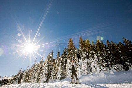 Téléchargez les photos : Une seule jeune femme profite d'une journée ensoleillée de ski d'hiver, vêtue d'un équipement complet de neige avec des bottes de ski et des lunettes de soleil - en image libre de droit